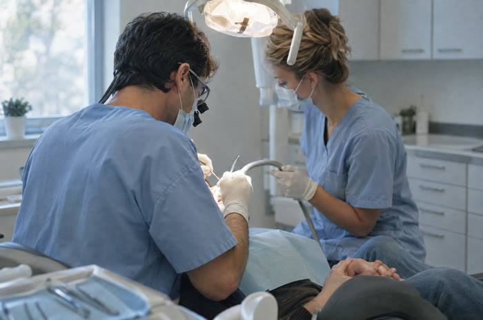 A dentist and an assistant treating a patient.
